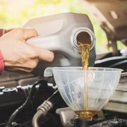 Car maintenance servicing mechanic pouring new oil lubricant into the car engine