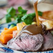 Gravy pouring onto meat roast dinner